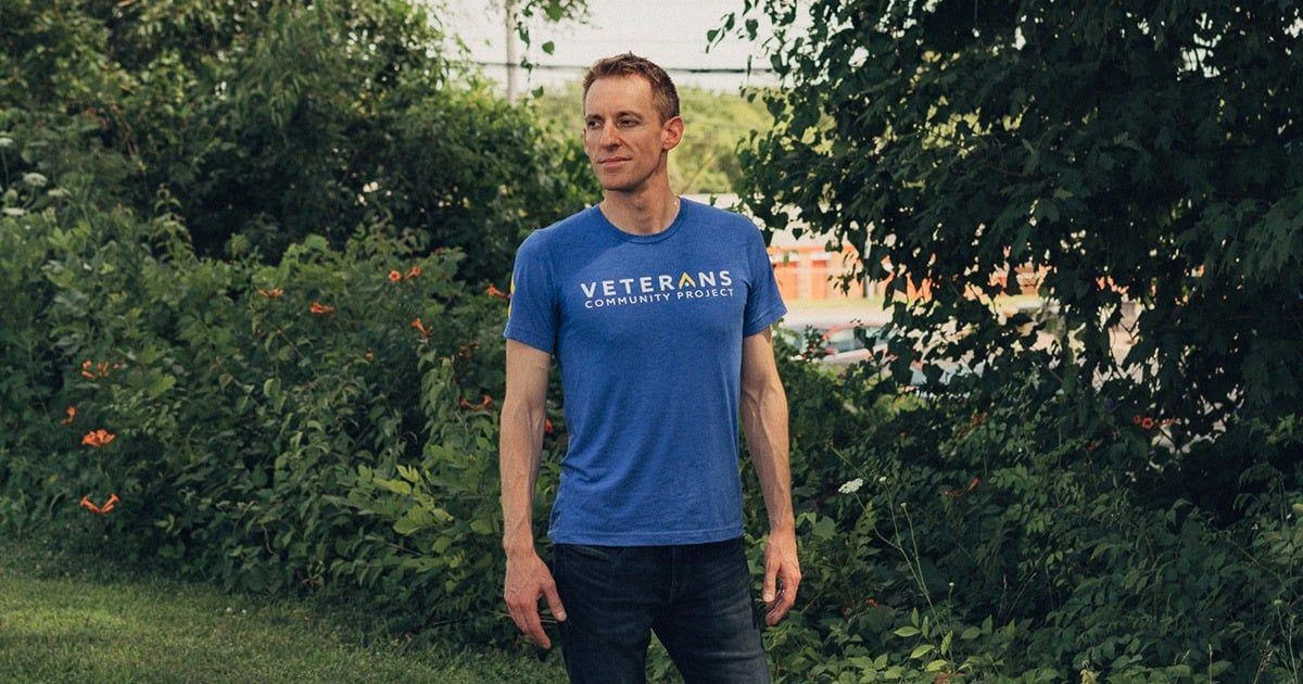 Jason Kander in a Veterans t-shirt standing in a garden